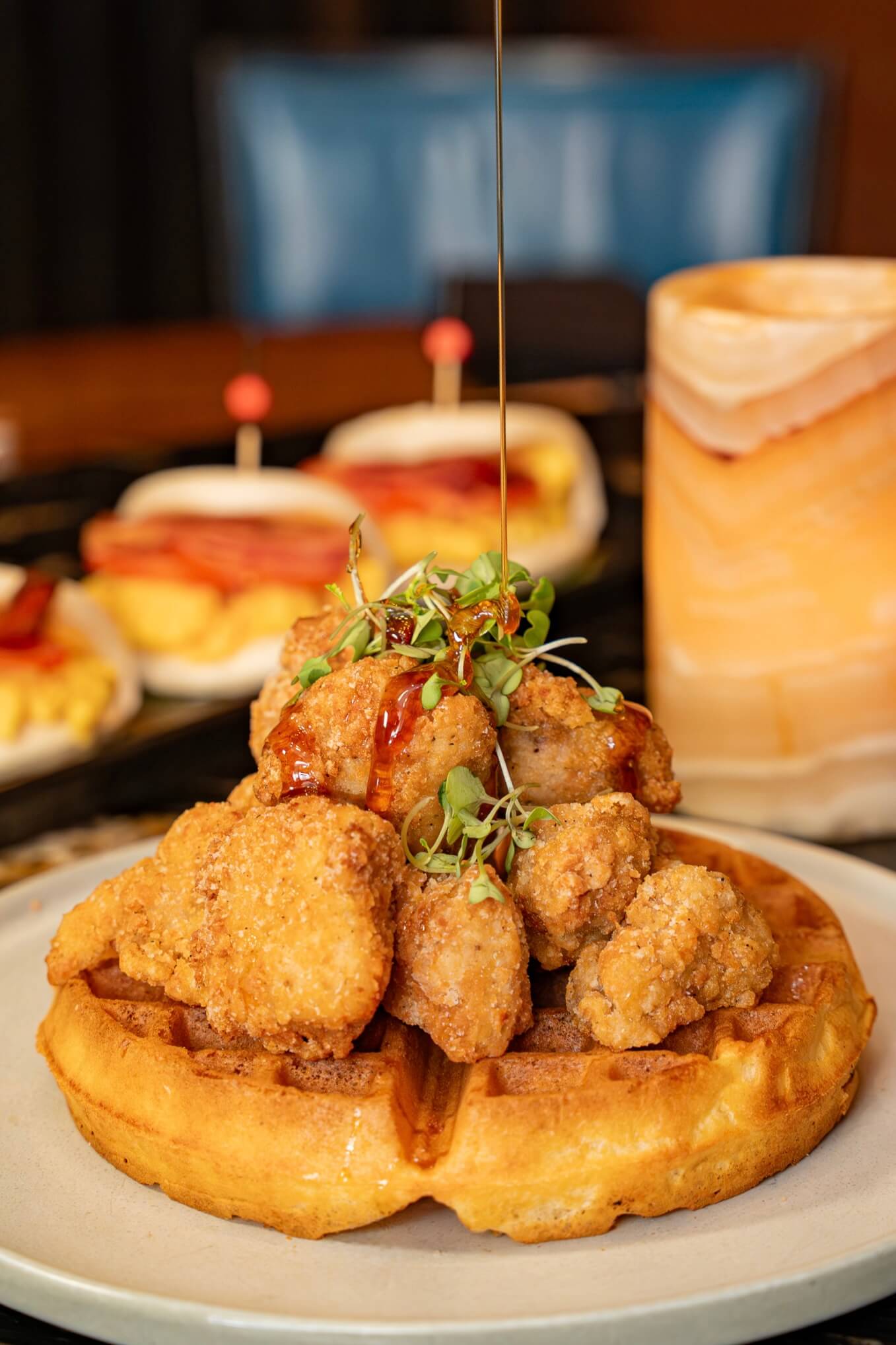 chicken and waffles covered in syrup and micro-greens