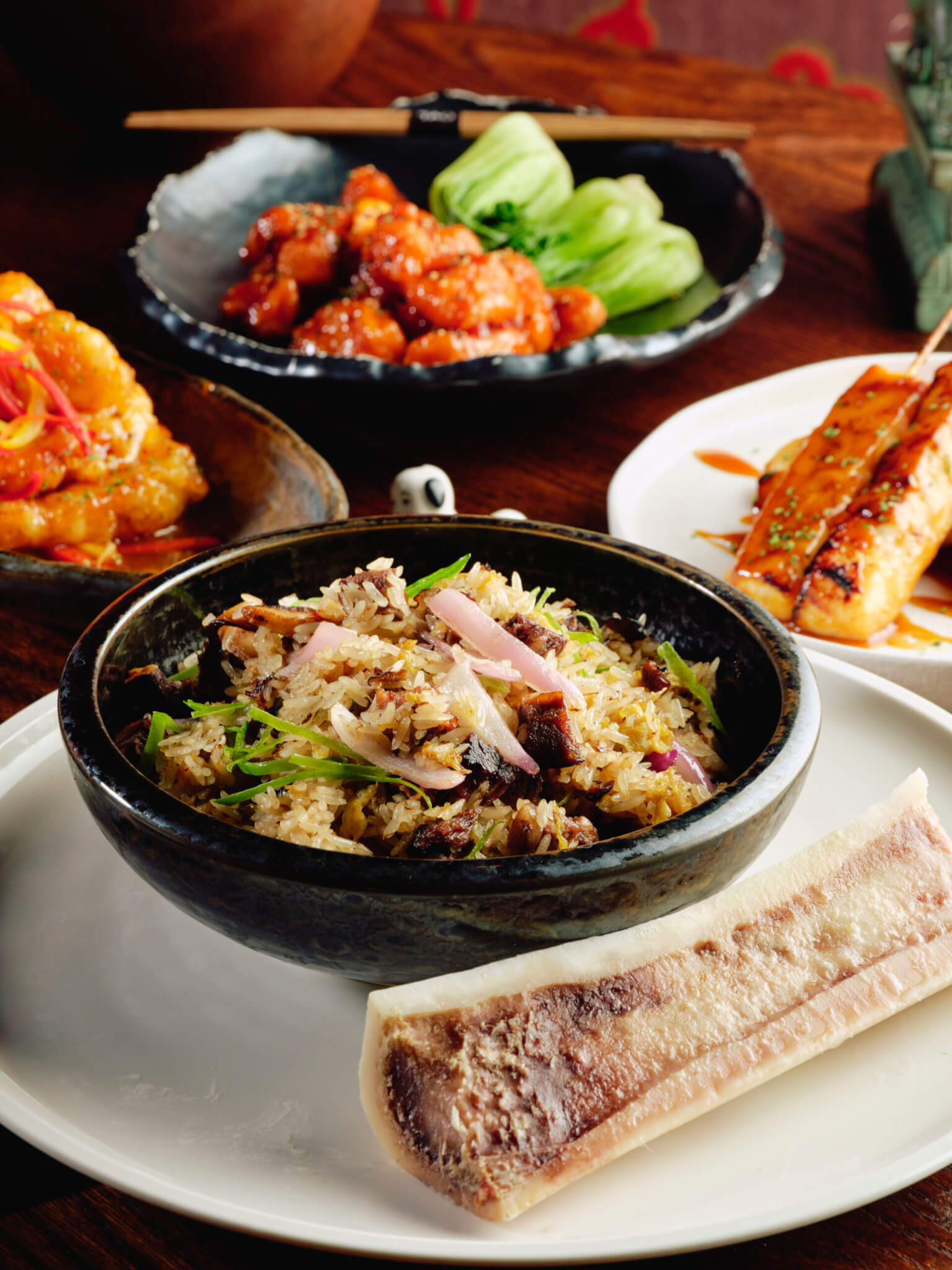 pork fried rice topped with shallots and bone marrow, orange chicken with bok choy, sea bass satay and sweet and sour pork
