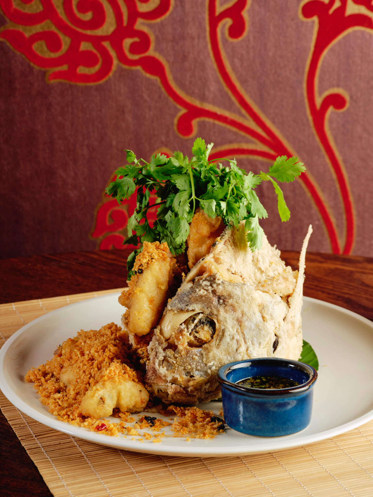 whole fried fish with dipping sauce topped with cilantro