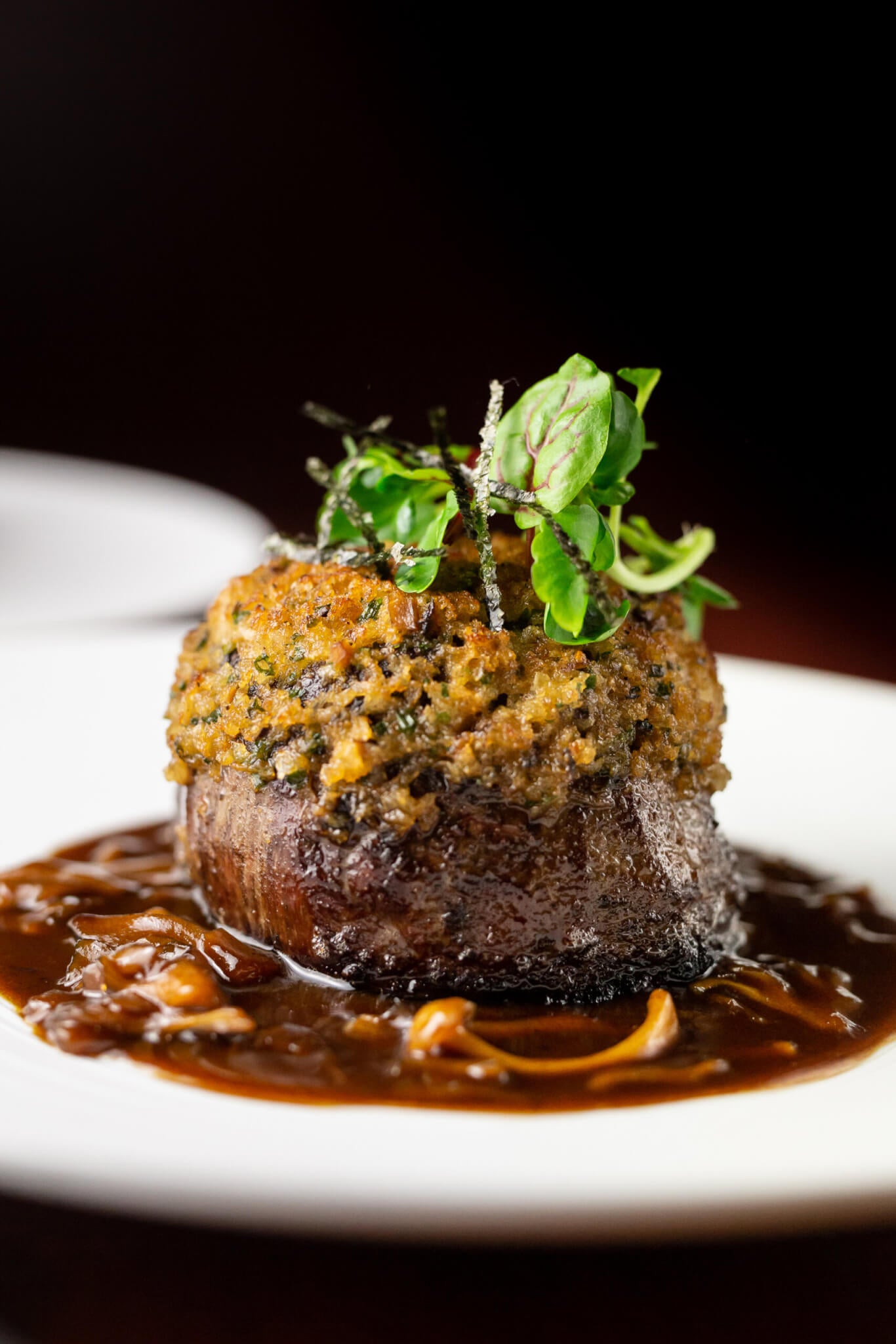 Steak with herb crust and greens on sauce with mushrooms