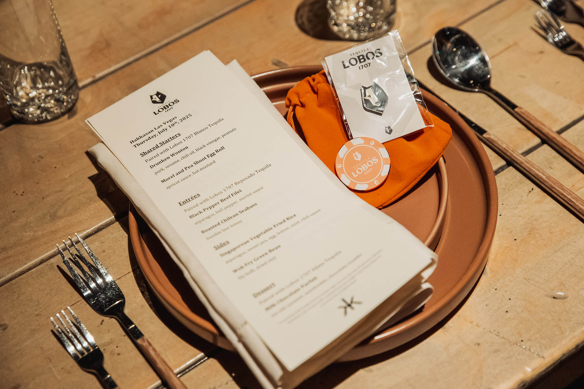 lobos tequila menu and poker chip and pin on plates with silverware