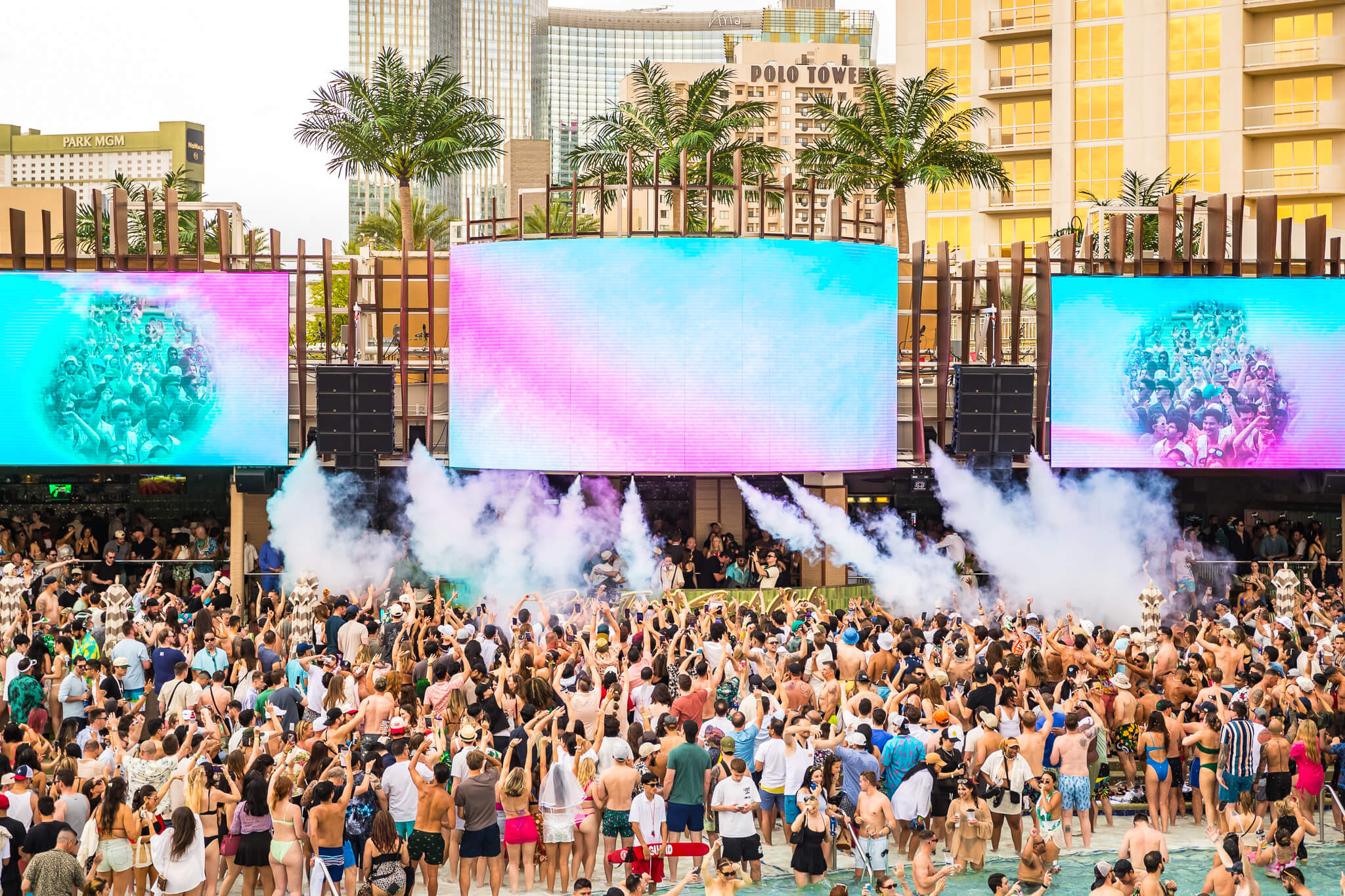 crowd at palm tree beach club and LED screens