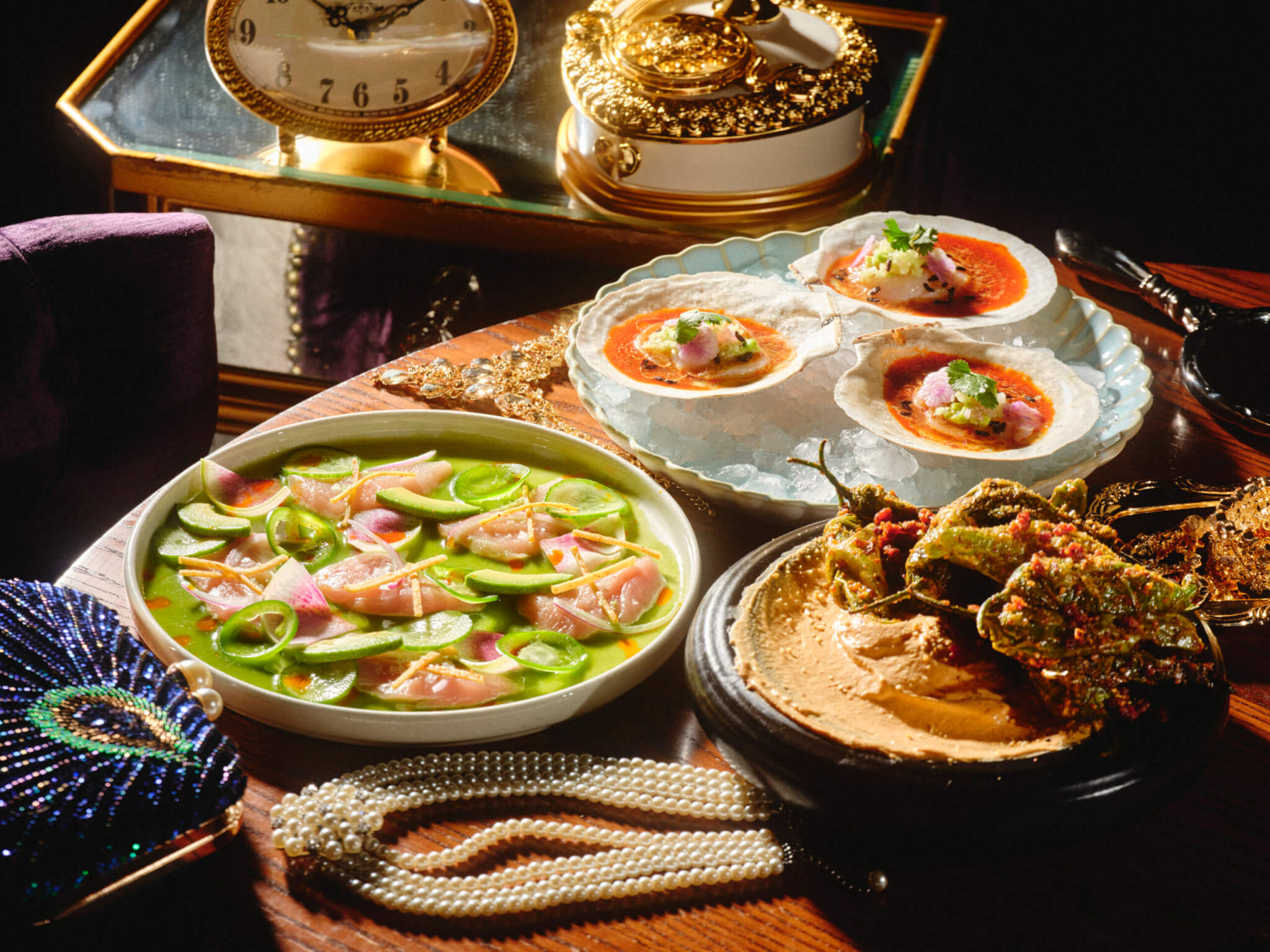 Scallop Crudo, poblano pepers and Hamachi Aguachile on plates next to jewelery
